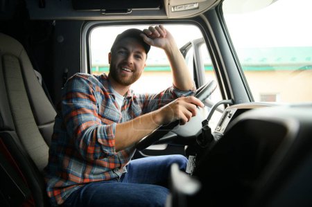 Foto de Vista lateral del conductor profesional detrás del volante en la cabina del camión - Imagen libre de derechos
