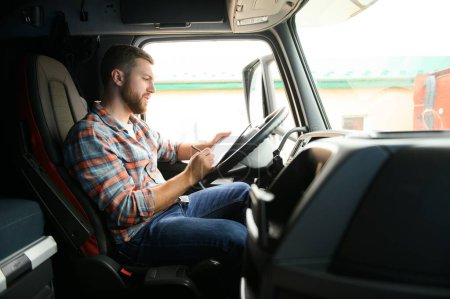Téléchargez les photos : Le chauffeur du camion regarde les documents pour la cargaison qu'il transporte - en image libre de droit