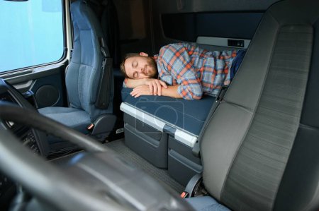 Téléchargez les photos : Chauffeur de camion dormant sur le lit intérieur de la cabine de camion. Style de vie des camionneurs - en image libre de droit