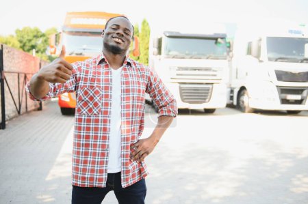 Foto de Conductor de camión negro cerca de su camión estacionado en un estacionamiento en una parada de camión - Imagen libre de derechos