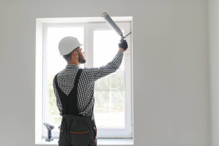 Téléchargez les photos : Travailleur de la construction installation fenêtre dans la maison. - en image libre de droit