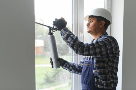 Téléchargez les photos : Travailleur indien utilisant un tube en silicone pour la réparation de la fenêtre intérieure. - en image libre de droit