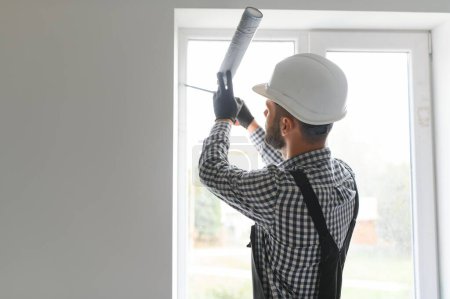 Téléchargez les photos : Travailleur de la construction installation fenêtre dans la maison. - en image libre de droit