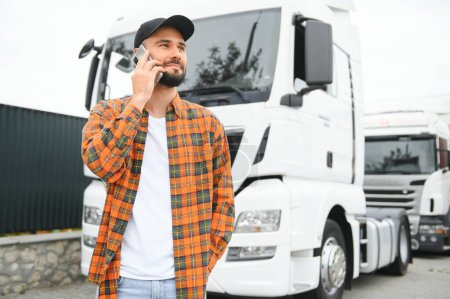 Foto de Hombre camionero hablando por teléfono por su camión blanco. - Imagen libre de derechos