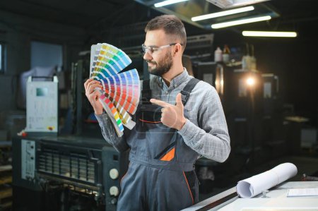 Foto de Tipógrafo de pie con muestras de color en la fabricación de la impresión. - Imagen libre de derechos