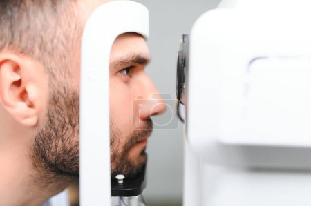 Téléchargez les photos : Un bel homme qui se fait examiner les yeux à la clinique d'ophtalmologie. Vérification de la rétine d'un œil masculin gros plan - en image libre de droit