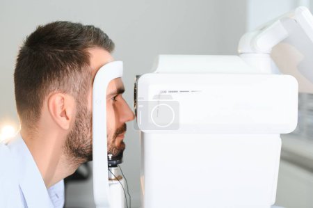 Téléchargez les photos : Un bel homme qui se fait examiner les yeux à la clinique d'ophtalmologie. Vérification de la rétine d'un œil masculin gros plan - en image libre de droit