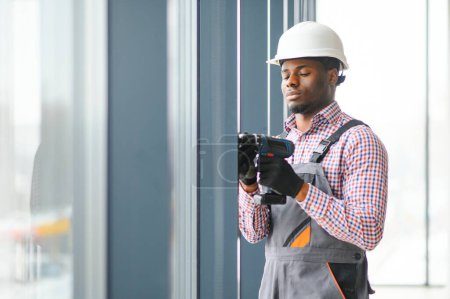 Téléchargez les photos : Vue Basse Angle D'un Jeune Réparateur Africain En Salopette Installer Une Fenêtre
. - en image libre de droit