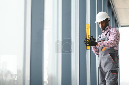 Téléchargez les photos : Vue Basse Angle D'un Jeune Réparateur Africain En Salopette Installer Une Fenêtre
. - en image libre de droit
