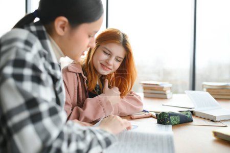 Studenten sitzen am gemeinsamen Schreibtisch und machen sich Notizen über das gemeinsame Lernen an der Universität.