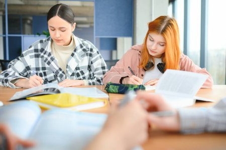 étudiants assis à un bureau partagé prendre des notes étudier ensemble à l'université.