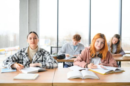 estudiantes se sientan en el escritorio compartido haciendo notas estudiando juntos en la universidad.
