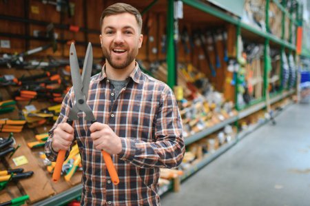 a customer chooses a garden shears for himself in a garden supply store.