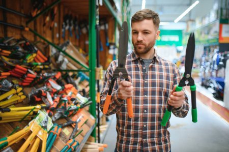 A man chooses garden shears in a hardware store