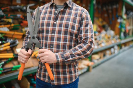 A man chooses garden shears in a hardware store