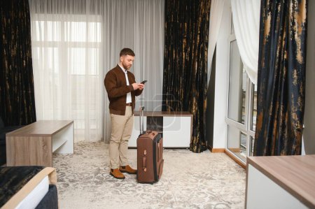 Jungunternehmer mit Koffer im Hotelzimmer. Geschäftsreisekonzept.