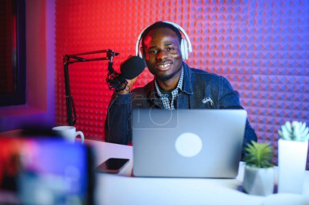 Un joven grabando o transmitiendo podcast usando micrófono en su pequeño estudio de transmisión. Creador de contenido