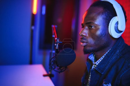 Un joven grabando o transmitiendo podcast usando micrófono en su pequeño estudio de transmisión. Creador de contenido