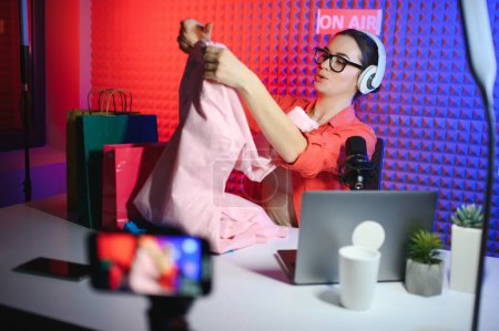 Female beauty blogger with fashionable clothes recording video in studio.