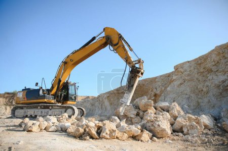 Marteau brise-roches hydraulique dans une carrière pour l'extraction de calcaire avec une excavatrice.