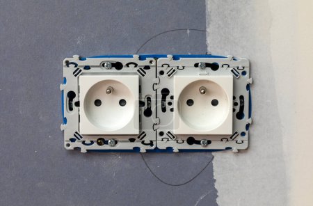Foto de Two-slot electrical outlet socket installation on blue wallboard - Imagen libre de derechos