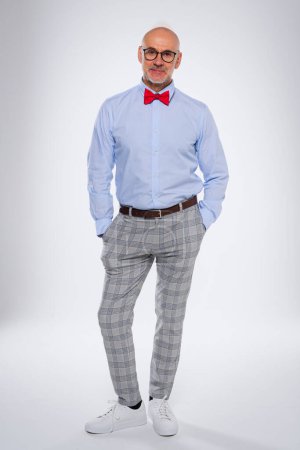 Photo for Full length of confident man standing with arms crossed at isolated white background. Smiling caucasian male wearing bow tie and checked trousers. Copy space. - Royalty Free Image