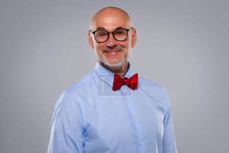 Photo for Close-up portrait of confident businessman standing at isolated grey background. Smiling male professional wearing eyewear and bow tie. Copy space. - Royalty Free Image
