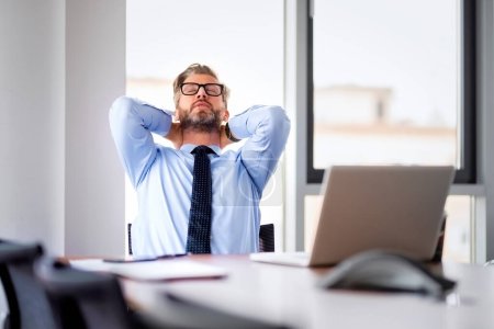 Téléchargez les photos : Shot of tired businessman sitting at office desk with his laptop - en image libre de droit