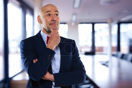 Photo for Confident businessman looking thoughtfully while standing in the boardroom. Male professional wearing suit and bow tie. - Royalty Free Image