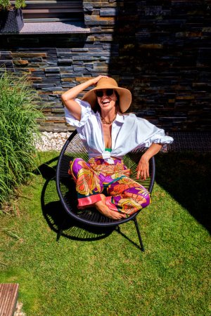 Foto de High angle shot of an attractive woman wearing straw hat and beachwear while relaxing outdoor. - Imagen libre de derechos