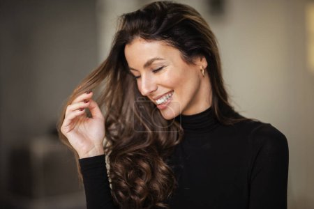 Photo for Close-up portrait of brunette haired woman cheerful smiling and playing her hand while standing indoor. - Royalty Free Image