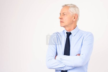 Photo for Studio half portrait of senior man wearing shirt and tie and standing with arms crossed at isolated background. Copy space. Side portrait. Copy space. - Royalty Free Image