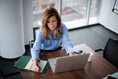 Photo for Shot of an executive businesswoman sitting at desk and working on laptop in a modern office. - Royalty Free Image