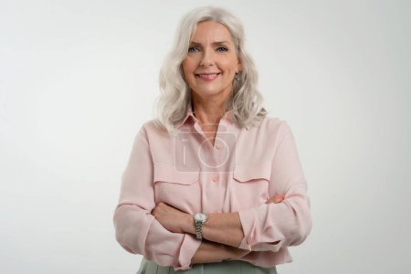 Photo for Studio portrait of grey haired senior woman looking at camera and smiling while standing at isolated white background. Copy space. - Royalty Free Image