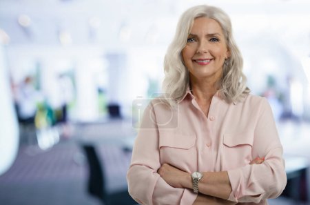 Photo for Studio portrait of grey haired senior businesswoman looking at camera and smiling while standing at the office. Copy space. - Royalty Free Image