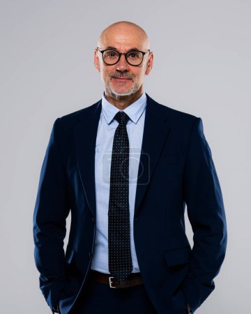 Photo for Portrait of mid aged business wearing glasses and suit and standing at isolated grey background. Copy space. - Royalty Free Image