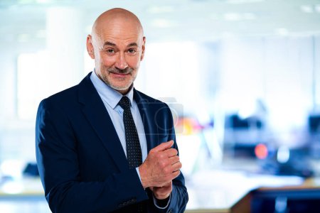 Téléchargez les photos : Un homme d'affaires en costume et cravate debout au bureau. Homme professionnel regardant caméra et sourire. - en image libre de droit