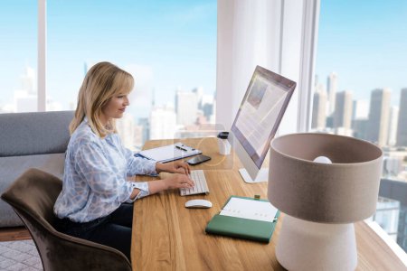 Foto de Mujer de negocios de mediana edad sentada en el escritorio y usando la computadora en la oficina. - Imagen libre de derechos