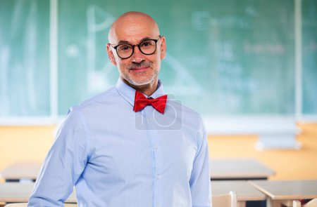 Photo for Portrait of mid aged professor standing in front of blackboard. Male teacher wearing glasses and bow tie. - Royalty Free Image