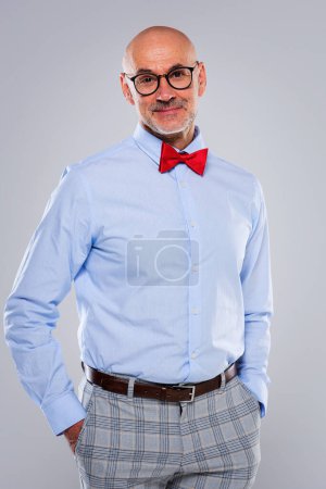 Photo for Studio portrait of a man wearing glasses and bow tie and standing at isolated backgroud. Copy space. - Royalty Free Image