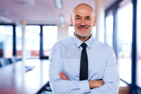 Foto de Retrato de hombre de negocios confiado en la oficina. Hombre profesional de mediana edad mirando a la cámara y sonriendo. Copiar espacio. - Imagen libre de derechos
