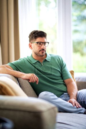 Photo for Portrait of a confident man relaxing on the sofa at home. Mid aged man wearing casual clothes. - Royalty Free Image