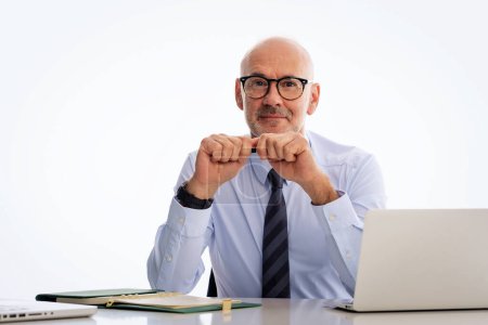 Photo for Mid aged businessman sitting at desk and using notebook for work against isolated background. Confident professional man wearing shirt and tie. Copy space. - Royalty Free Image