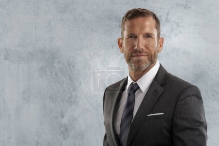 Photo for Portrait of mid aged businessman standing at isolated grey background. Executive professional man wearing suit and tie. Copy space. - Royalty Free Image