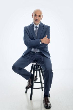 Photo for Full length of mid agd man wearing suit and sitting against isolated white background. Copy space. - Royalty Free Image