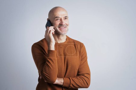 Photo for Studio portrait of a mid aged man wearing casual clothes and using smartphone against isolated background. Copy space. - Royalty Free Image