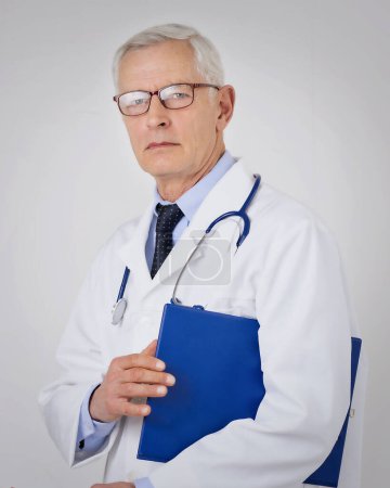 Porträt eines grauhaarigen Arztes vor isoliertem Hintergrund. Professioneller Mann im Laborkittel und mit Klemmbrett in der Hand.