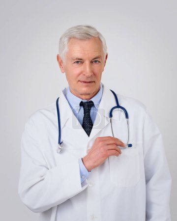 Porträt eines grauhaarigen Arztes vor isoliertem Hintergrund. Berufskraftfahrer trägt Labormantel und Stethoskop um den Hals.