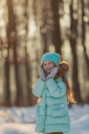 Photo for Girl in a turquoise squat and a hat in a winter forest, shot vertically - Royalty Free Image