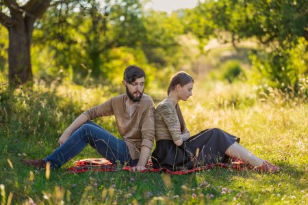 Photo for Couple sitting in nature with their backs to each other - Royalty Free Image